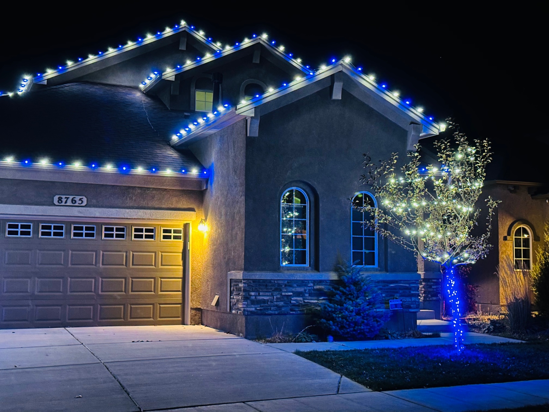Blue and cool white roofline lighting on a stucco home