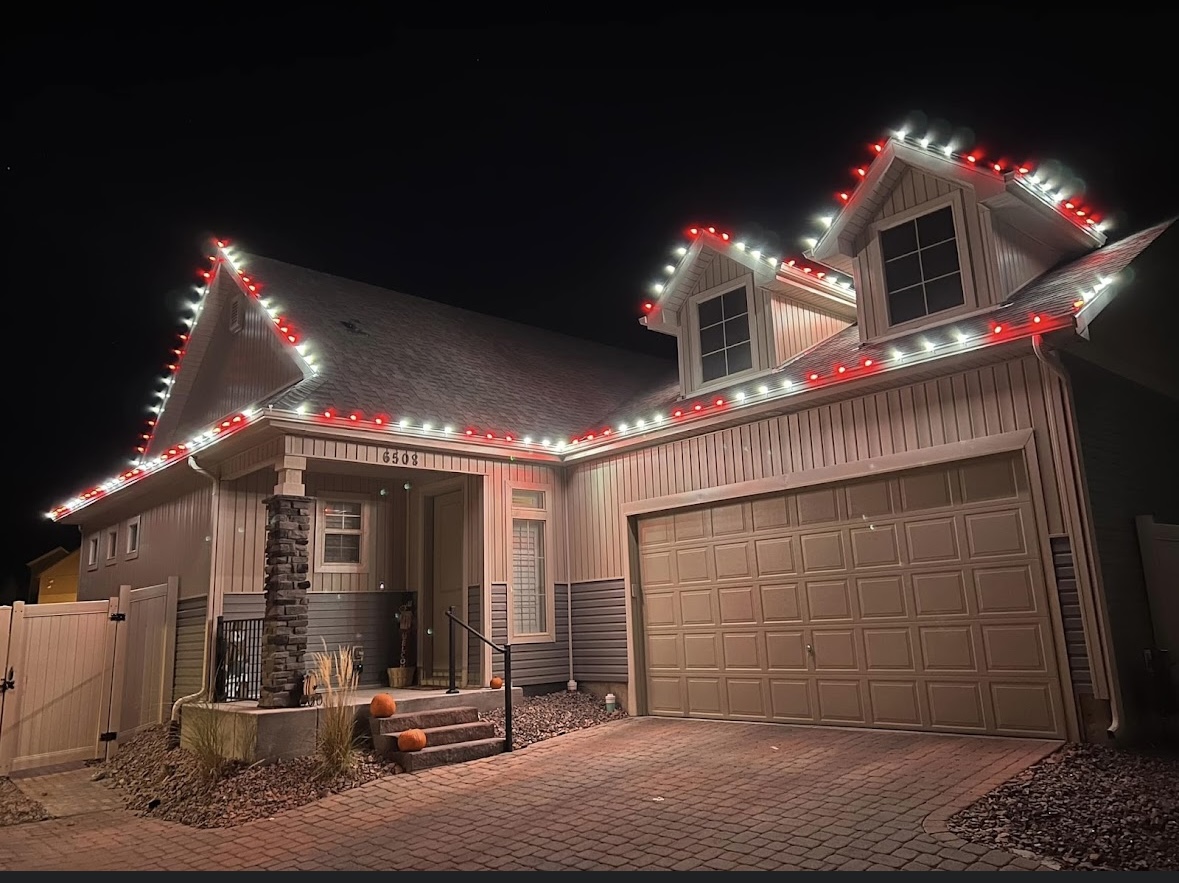 Red and white Christmas roofline lighting on a front porch home