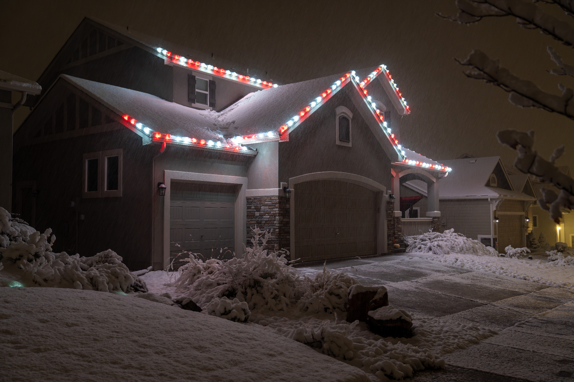 Red and white Christmas roofline lighting during a snowstorm