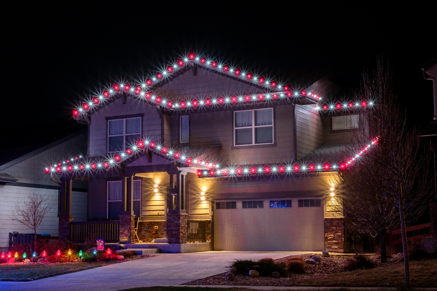 Red and white double-row Christmas lights on a two-story home