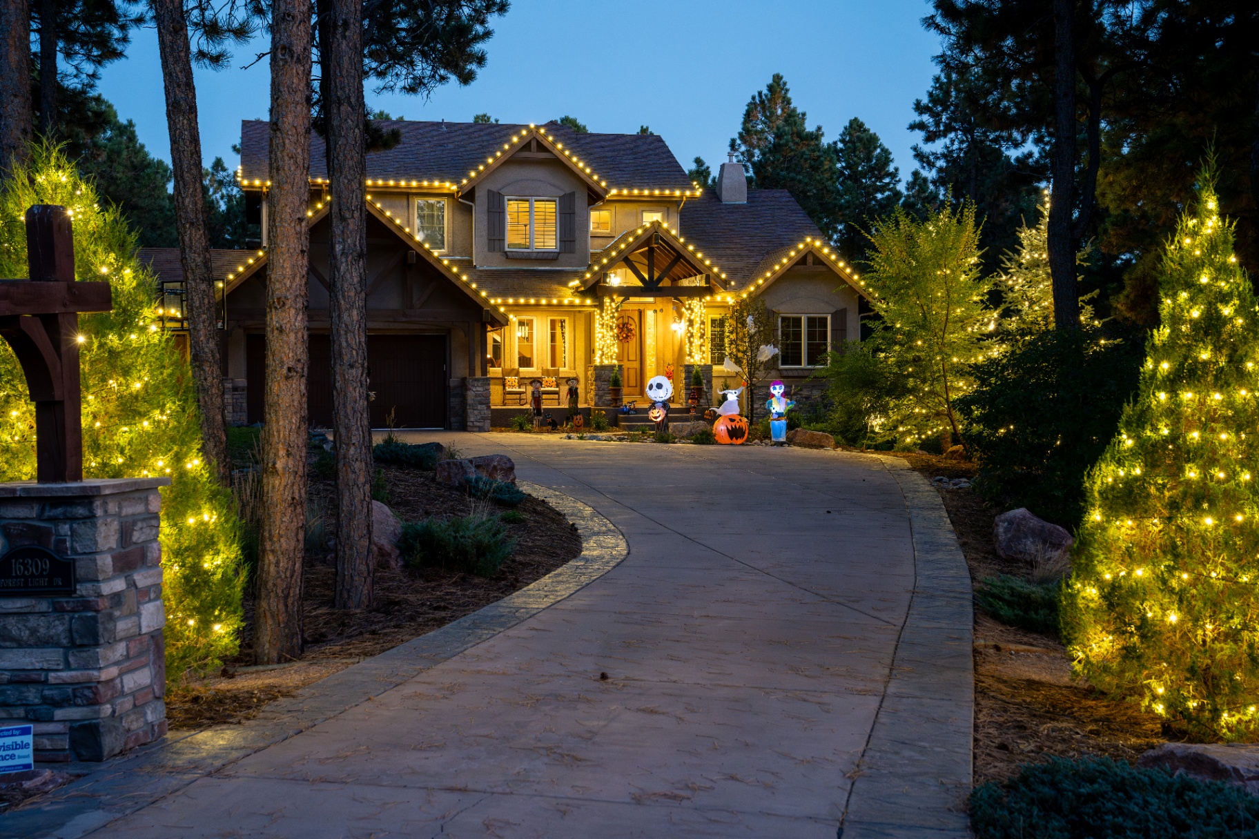 Warm white roofline lights with wrapped trees and Halloween decor